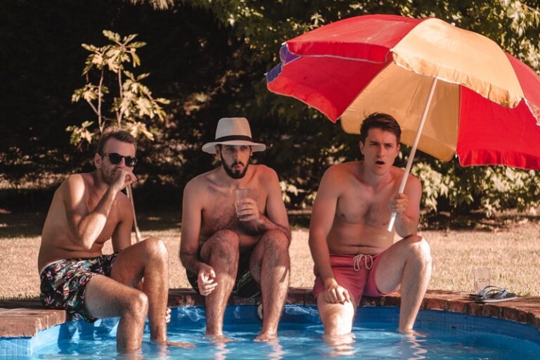 Trzech mężczyzn w basenie z parasolem latem