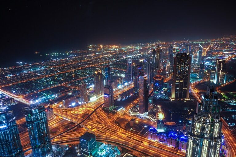 Widok na Dubaj nocą z oświetlonymi budynkami i drogami