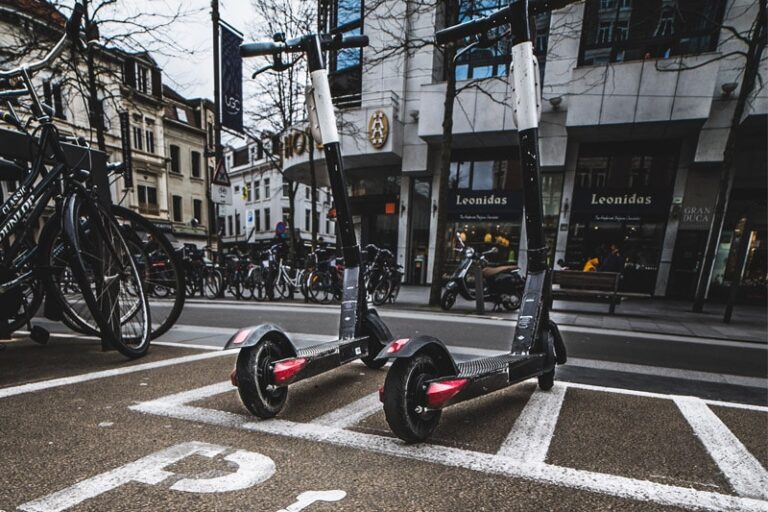 Hulajnogi zaparkowane na ulicy obok rowerów