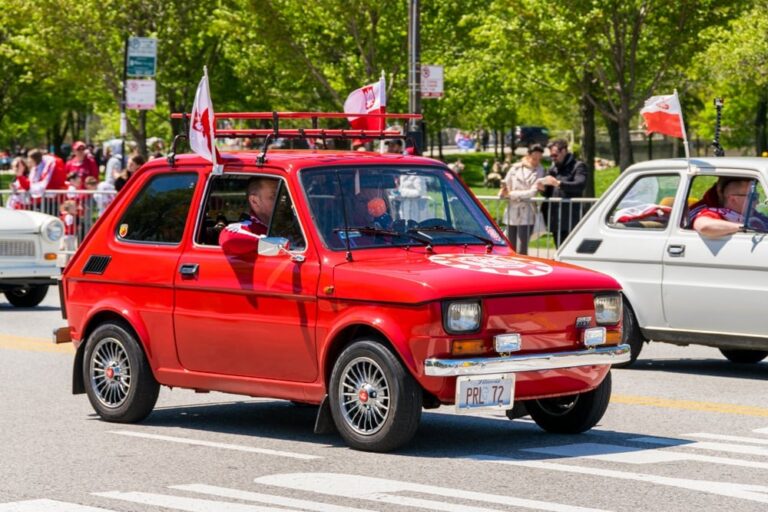 Czerwony samochód maluch z flagami w parku