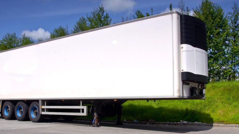 Naczepa chłodnicza na parkingu w otoczeniu drzew