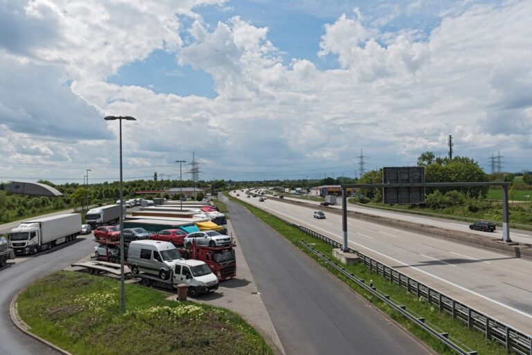 Parking przy autostradzie z ciężarówkami i samochodami.