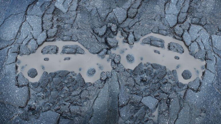 Woda w dziurze na drodze z odciskami opon