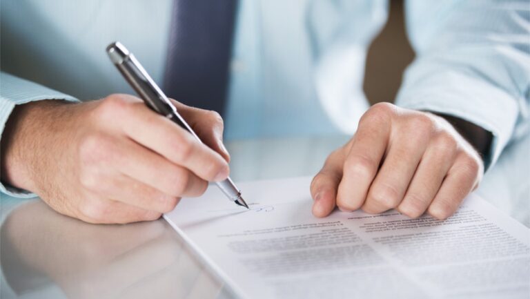 Osoba podpisująca dokument na biurku