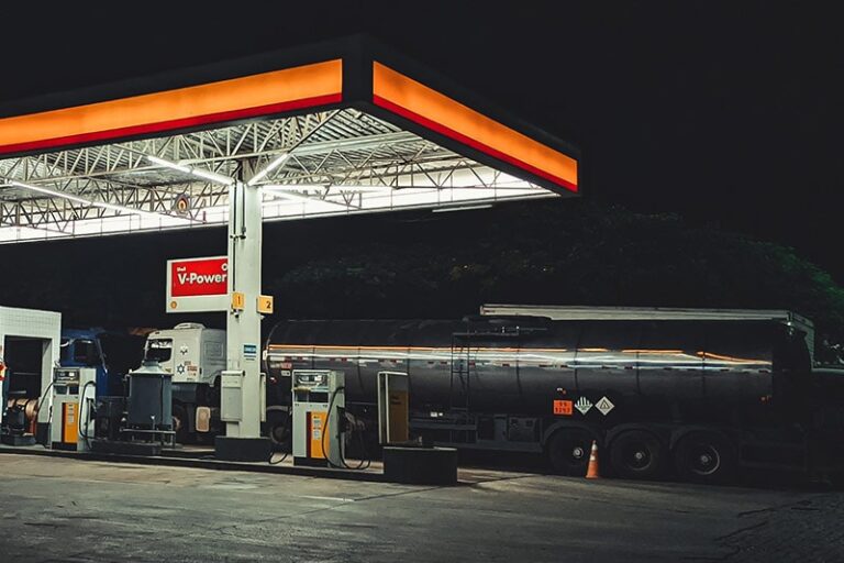 Stacja benzynowa nocą z cysterną i dystrybutorami.