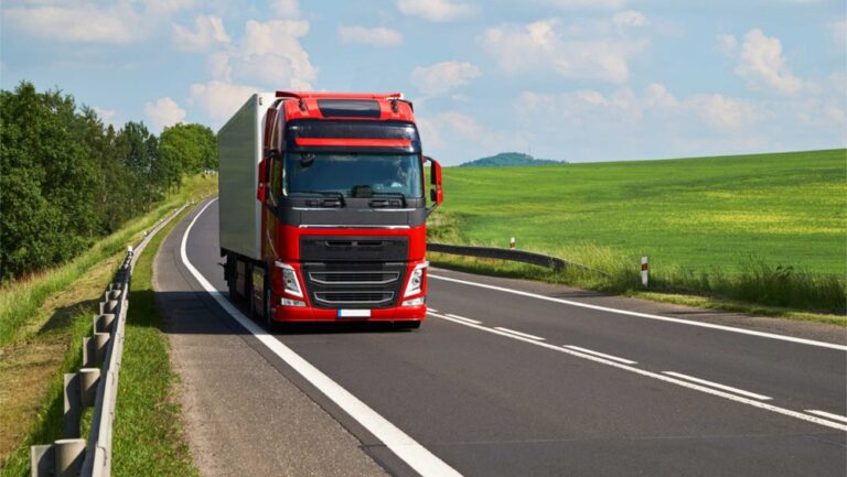 Czerwony tir na drodze w zielonym krajobrazie