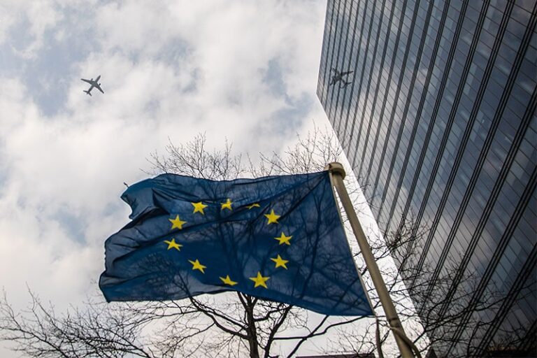 Flaga Unii Europejskiej na tle budynku i samolotu