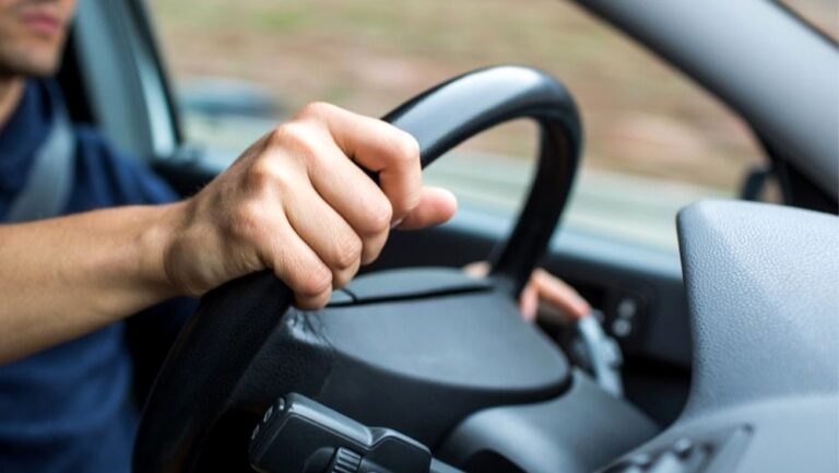 Ręka kierowcy trzymająca kierownicę samochodu